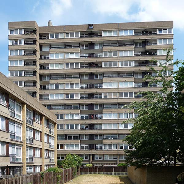 Photograph of a high-rise brutalist-style apartment complex in London: lines of windows alternate with stretches of cement to create a stacked effect.