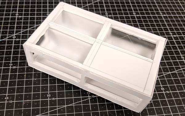 Side 2 of foam core table model F, the top below the framing is fogged glass, and the solid corner of the top is above open sides. The back-left corner sides, through the fogged glass, are seen to be fully solid