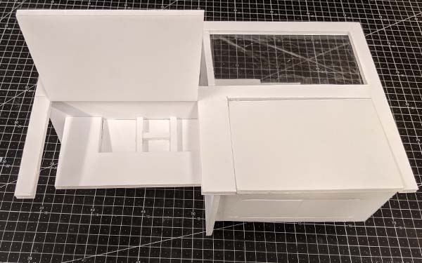 Side 2 of foam core table model I. The left solid panel opens to reveal a multi-sectioned storage area, the right solid panel remains closed and the front of the table is also solid, with lines denoting cabinet doors.