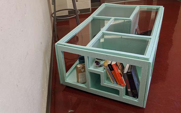 Side 2 of the full-scale foam table model shows the stair “room” and a section of the adjacent rectangular “room.” The stairs have an open section below and the rectangular room is seen to hold a box of teabags and a coffee mug. 