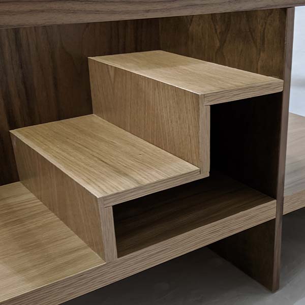 An upclose image of the “entryway” stairs. They’re made from the same white oak as the base of the table, and create a small cubby space in addition to the tiered shelf space on top of the stairs. 